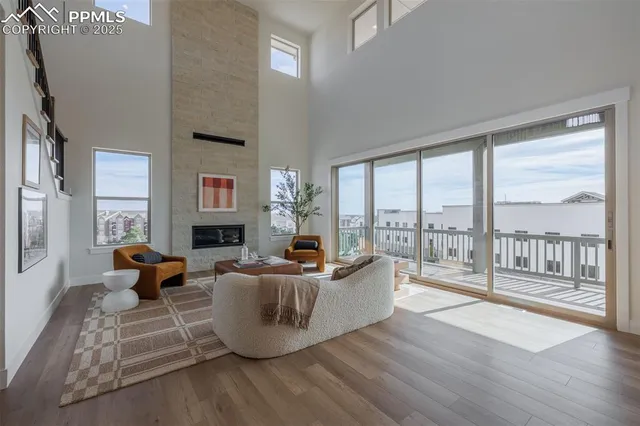 a living room with furniture large windows and wooden floor