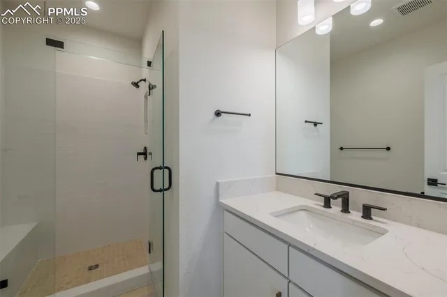 a bathroom with a granite countertop sink a mirror and shower