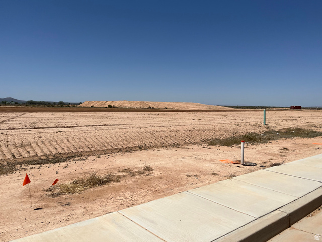 5107 North 75 East, Unit 207 Enoch, UT 84721 - Photo 1 of 13 Expansive land parcel featuring clear ground preparation, a concrete sidewalk and curb, and visible utility stubs for future development