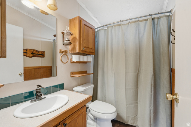 8066 North Valley View Heights Preston, ID 83263 - Photo 22 of 34 Bathroom featuring a vanity with a drop-in sink, wood-finish cabinetry, teal tile backsplash, and a wall-mounted medicine cabinet