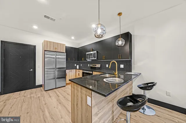 a kitchen with stainless steel appliances granite countertop a sink a stove and refrigerator