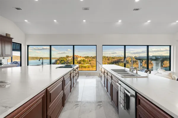 a view of a kitchen with kitchen island a large window a sink and cabinets