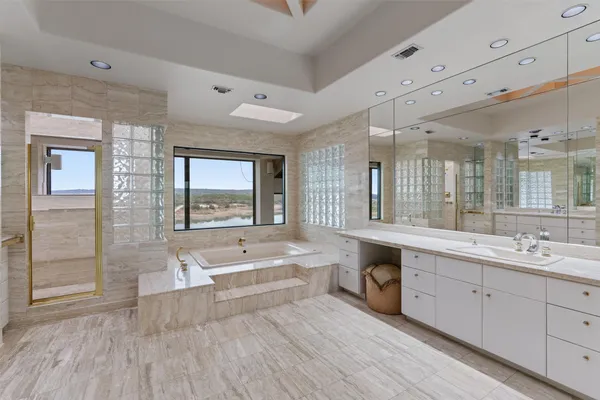 a spacious bathroom with a double vanity sink a large mirror and a bathtub