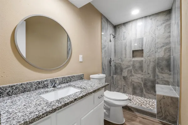 a bathroom with a granite countertop sink a toilet and a shower