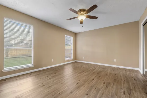 an empty room with wooden floor and windows