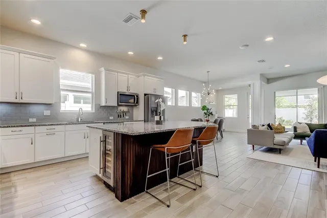 a kitchen with stainless steel appliances granite countertop a sink dishwasher and white cabinets with wooden floor