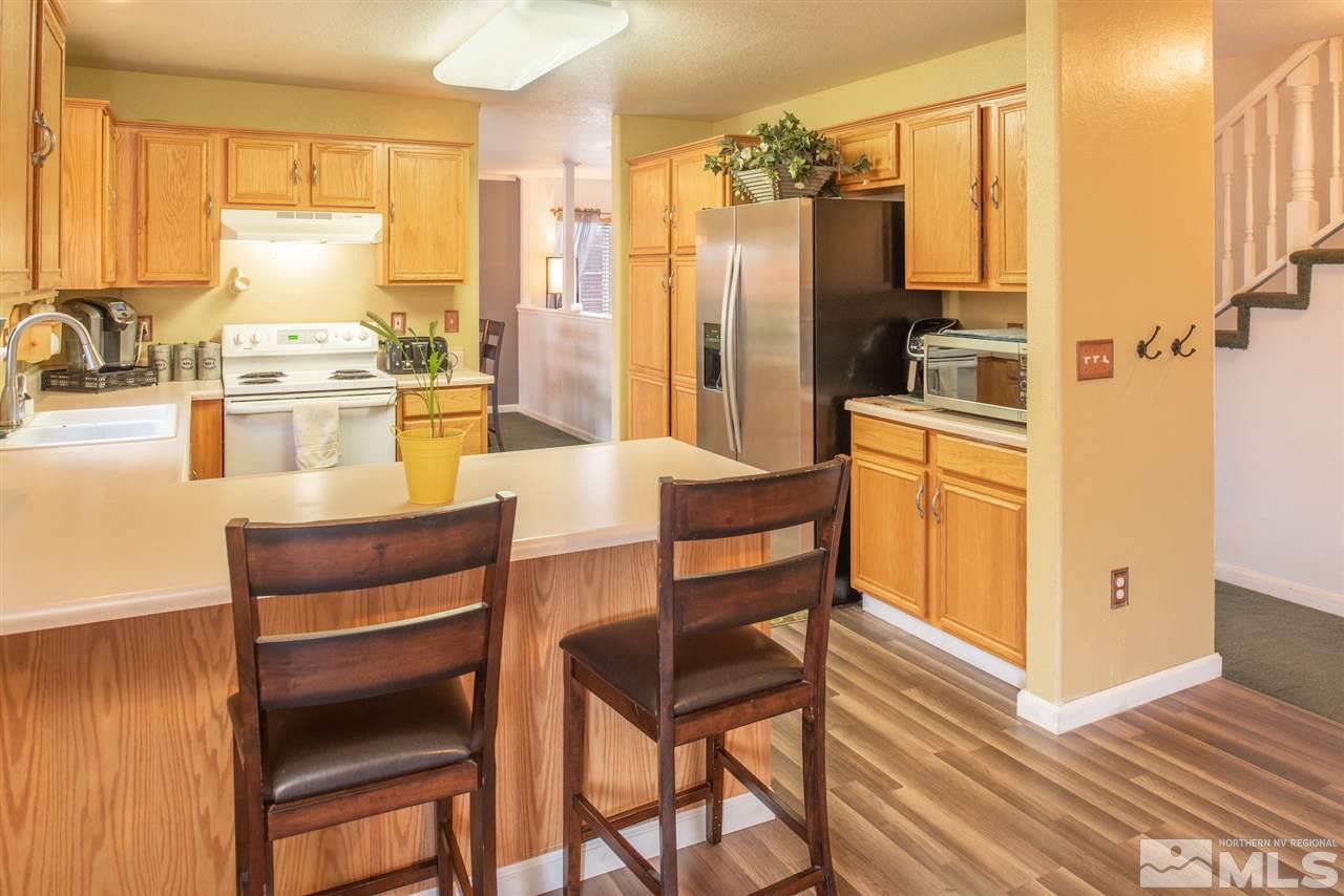 18205 Fontana Court Reno, NV 89508 - Photo 10 of 27 a kitchen with a refrigerator a stove and white cabinets with wooden floor