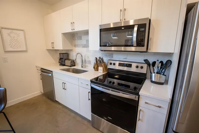 a kitchen with stainless steel appliances a stove a microwave a sink and cabinets