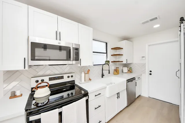 a kitchen with stainless steel appliances a stove microwave and sink