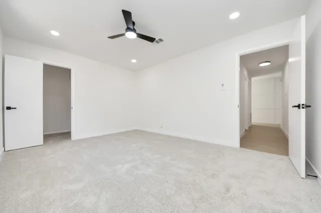 an empty room with a ceiling fan and carpet