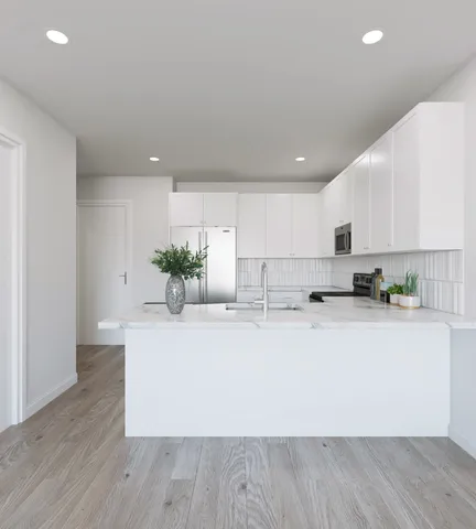 a large white kitchen with wooden floor and stainless steel appliances