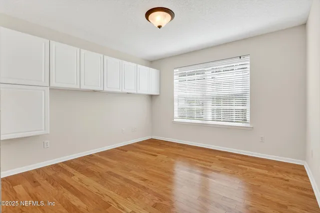 a view of an empty room with window and cabinet