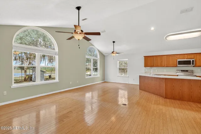 a view of empty room with wooden floor and fan