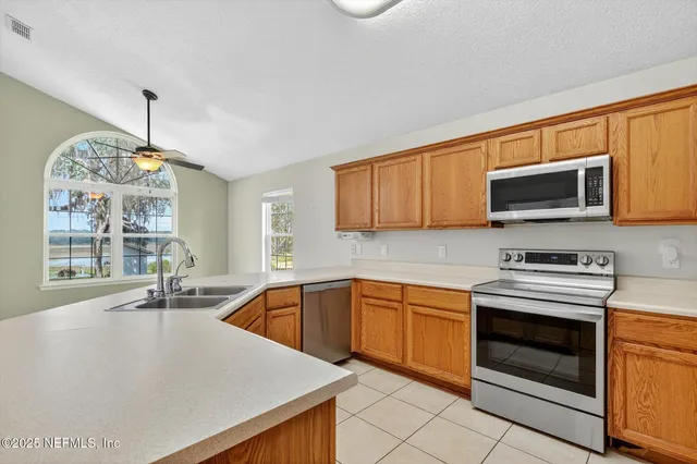 a kitchen with stainless steel appliances granite countertop a sink a microwave and a refrigerator