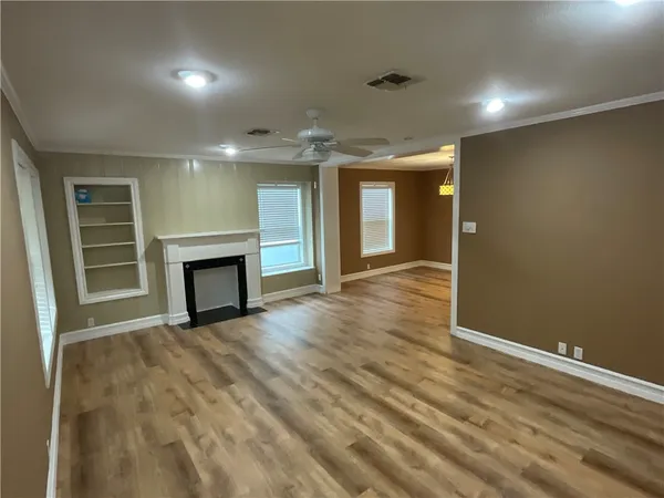 an empty room with wooden floor fireplace and windows