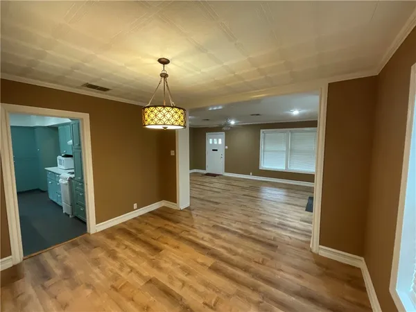 a view of an empty room with wooden floor and a bathroom