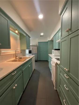 a large kitchen with a sink and refrigerator