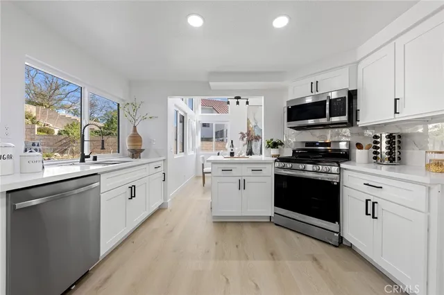 a kitchen with granite countertop a sink stainless steel appliances and cabinets