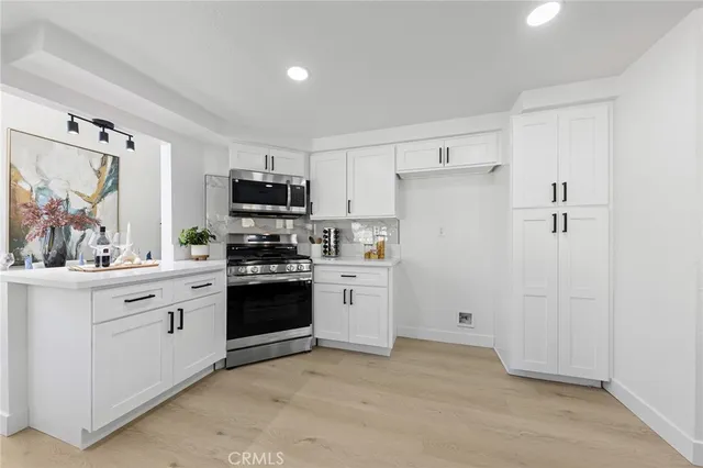 a kitchen with white cabinets and stainless steel appliances