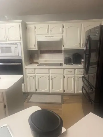 a kitchen with white cabinets and a refrigerator