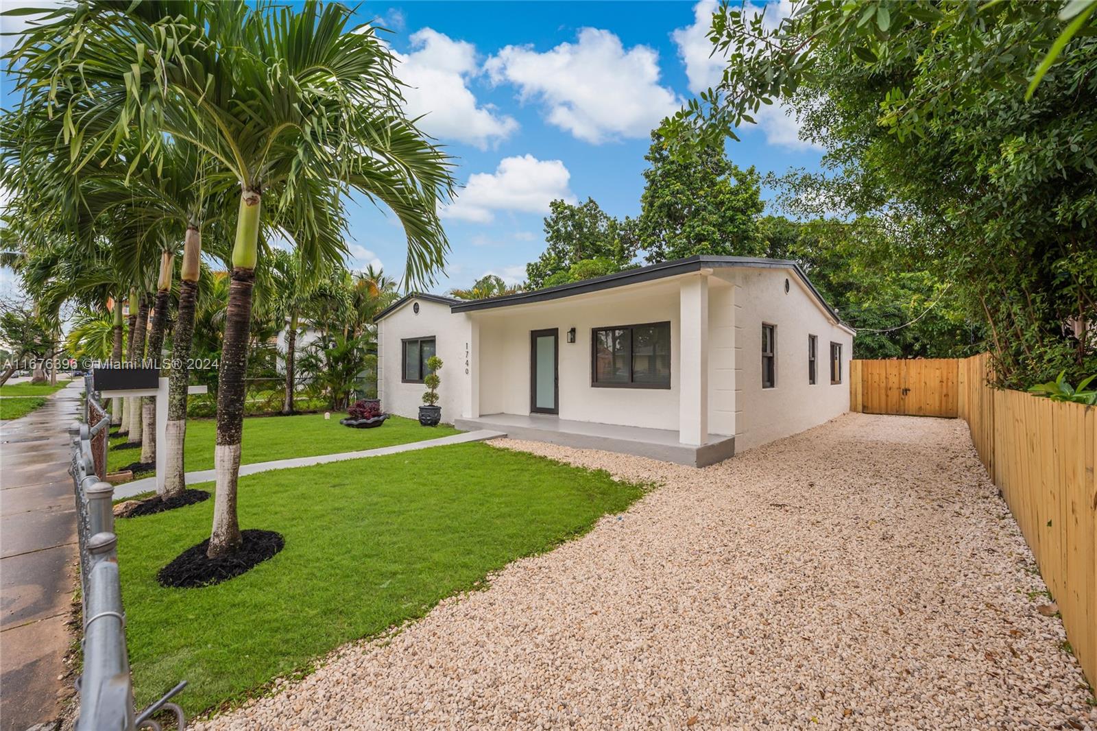 1740 Northwest 53rd Street Miami, FL 33142 - Photo 2 of 25 a white house that has a big yard and large trees
