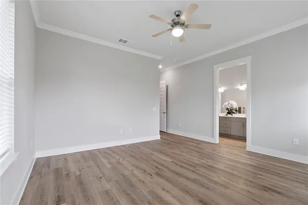 an empty room with wooden floor and a ceiling fan