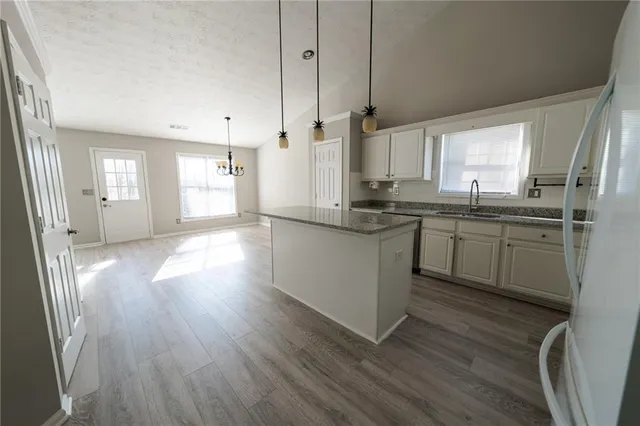 a kitchen with stainless steel appliances granite countertop a sink a stove a refrigerator and wooden floor