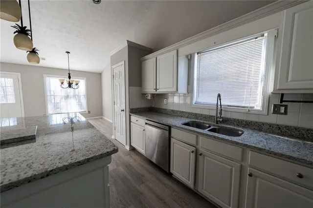 a kitchen with kitchen island granite countertop a sink window and cabinets