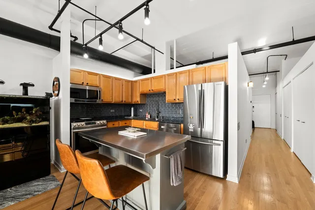 a kitchen with stainless steel appliances a stove a refrigerator and a dining table