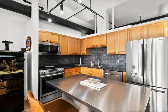 a kitchen with stainless steel appliances granite countertop a refrigerator a stove and a sink with cabinets