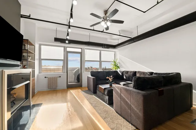 a living room with furniture a flat screen tv and a refrigerator