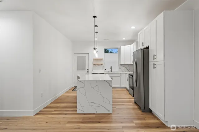 a kitchen with stainless steel appliances a refrigerator and wooden floor