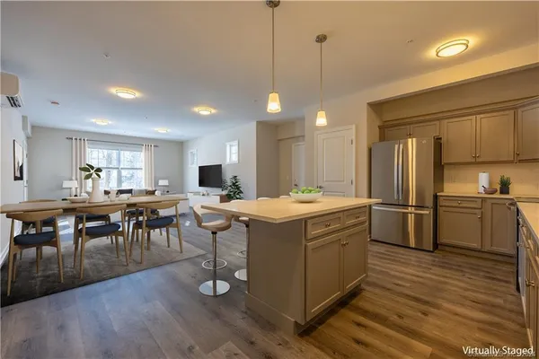 a kitchen with stainless steel appliances granite countertop a stove a refrigerator a kitchen island a dining table and chairs with wooden floor