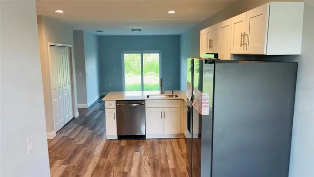 a kitchen with a refrigerator stove and wooden floor
