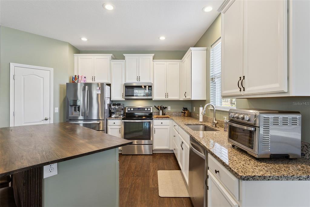 2400 Artist Point Court Apopka, FL 32703 - Photo 12 of 50 a kitchen with stainless steel appliances granite countertop a stove top oven a sink dishwasher and a refrigerator with wooden floor
