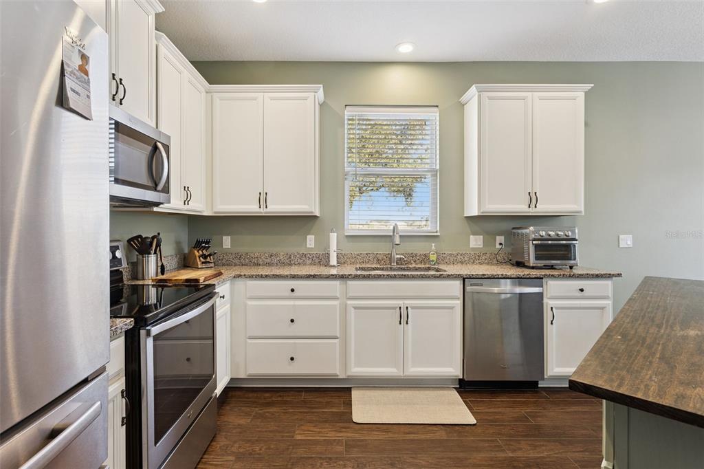 2400 Artist Point Court Apopka, FL 32703 - Photo 13 of 50 a kitchen with granite countertop cabinets stainless steel appliances a sink and a window