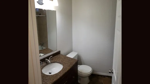 a bathroom with a granite countertop toilet sink and mirror