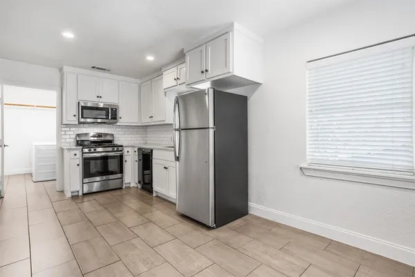 a kitchen with granite countertop a refrigerator and a stove top oven