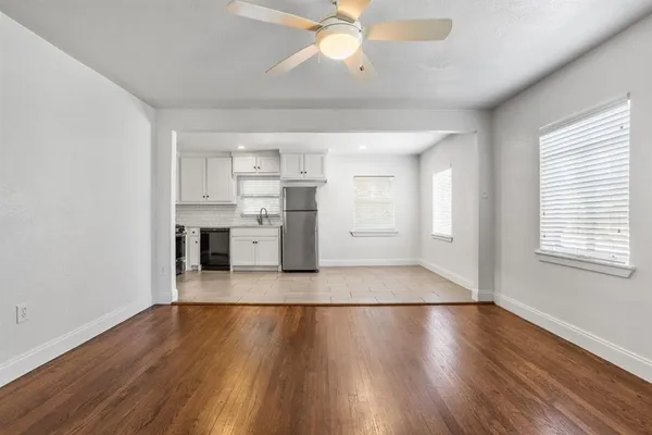 a view of an empty room with wooden floor and a window