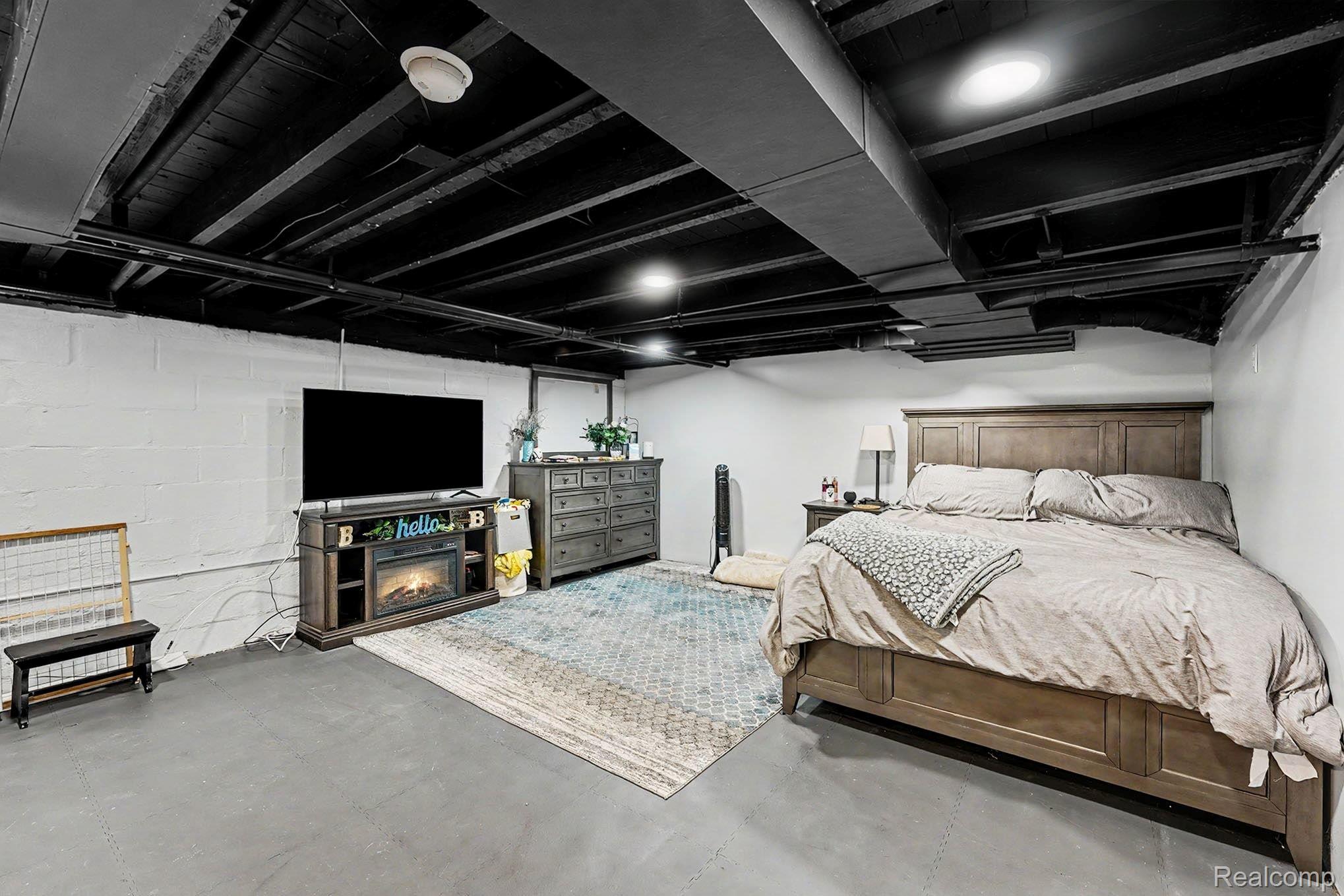 8215 Clinton River Road Sterling Heights, MI 48314 - Photo 18 of 28 Finished lower level space with painted concrete flooring, painted white block walls, and a black-painted exposed ceiling
