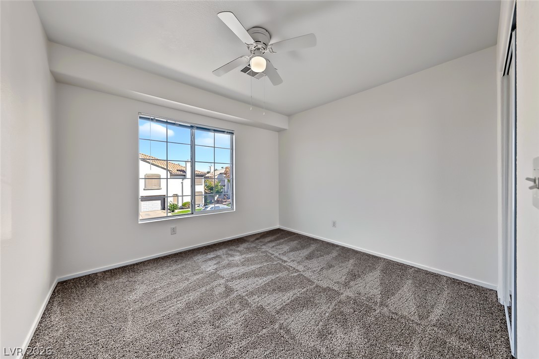 205 Genesee Point Street Henderson, NV 89074 - Photo 19 of 30 Plush carpeting and a large multi-pane window create a welcoming secondary bedroom space.