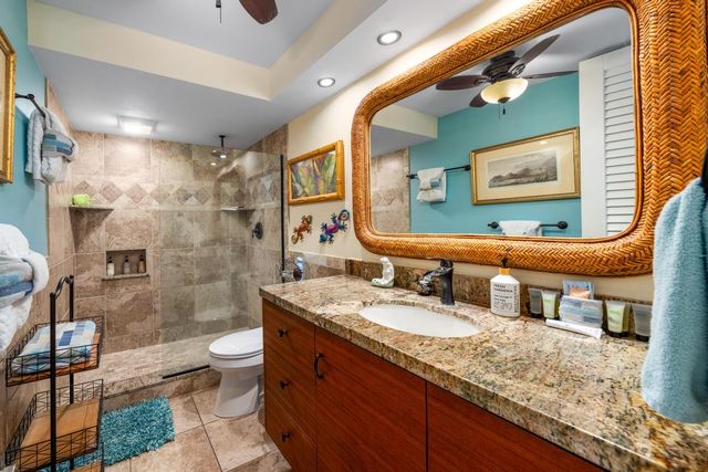 a bathroom with a granite countertop double vanity sink a mirror and a shower