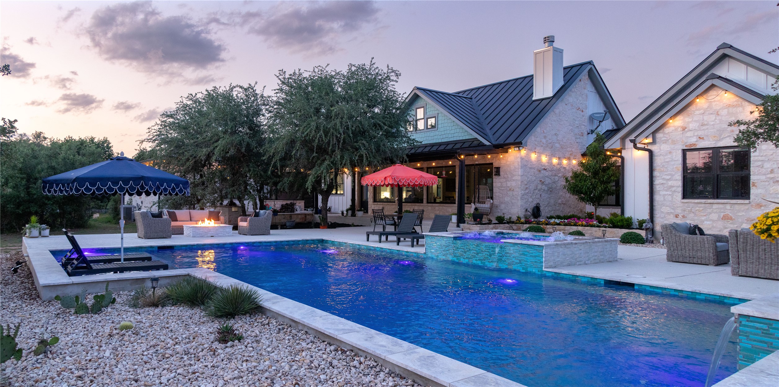 272 Slate Rock Road Fredericksburg, TX 78624 - Photo 9 of 32 Twilight descends upon a luxurious backyard oasis, featuring a glistening pool, inviting fire pit, and ample space for relaxation.