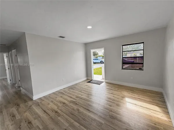 a view of empty room with wooden floor and window