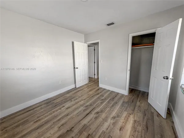 a view of an empty room with closet and a window