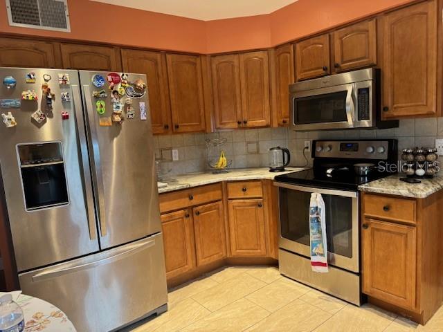2457 Ravendale Court Kissimmee, FL 34758 - Photo 13 of 17 a kitchen with stainless steel appliances granite countertop a refrigerator stove and microwave