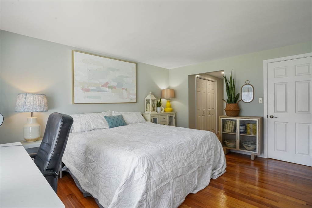 1 Commodore Court, Unit 104 Hull, MA 02045 - Photo 17 of 35 a bedroom with a bed and wooden floor