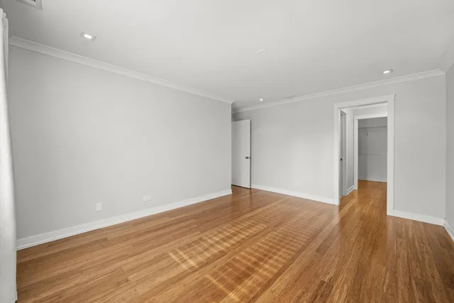a view of an empty room with wooden floor and closet