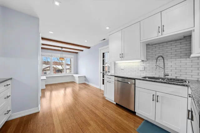 a kitchen with granite countertop wooden floors appliances cabinets and a sink
