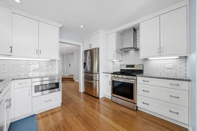 a kitchen with stainless steel appliances white cabinets and a refrigerator